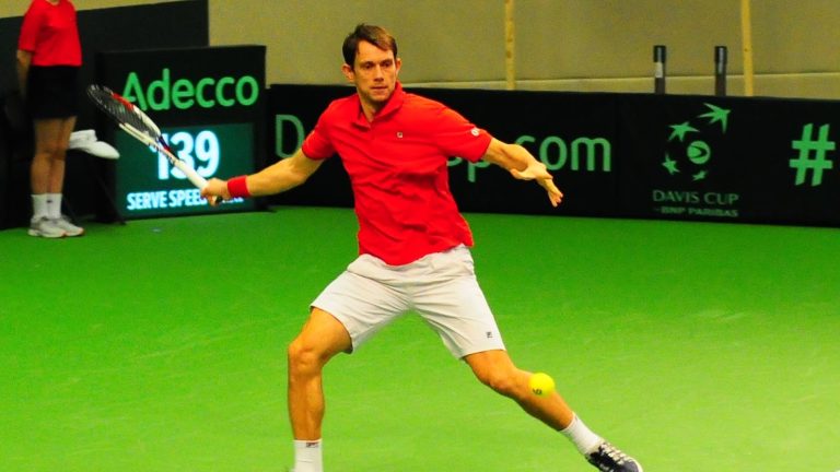 Frederik Løchte Nielsen slår forhånd i rød dansk landsholdstrøje under en Davis Cup-kamp indendørs