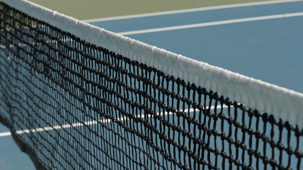 Tennisnet i nærbillede foran en blå hardcourt-bane