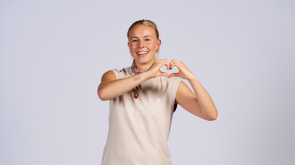 Mia Blichfeldt smiler og former et hjerte med hænderne i den danske OL-dragt