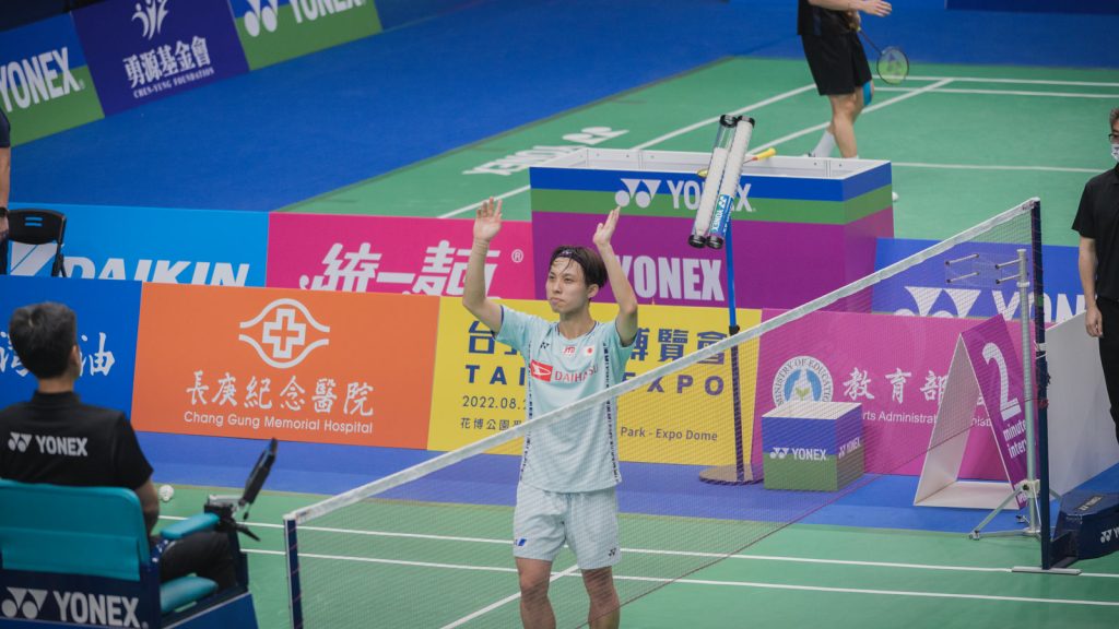 Kodai Naraoka løfter begge arme over hovedet på badmintonbanen efter en sejr ved Taipei Open 2022