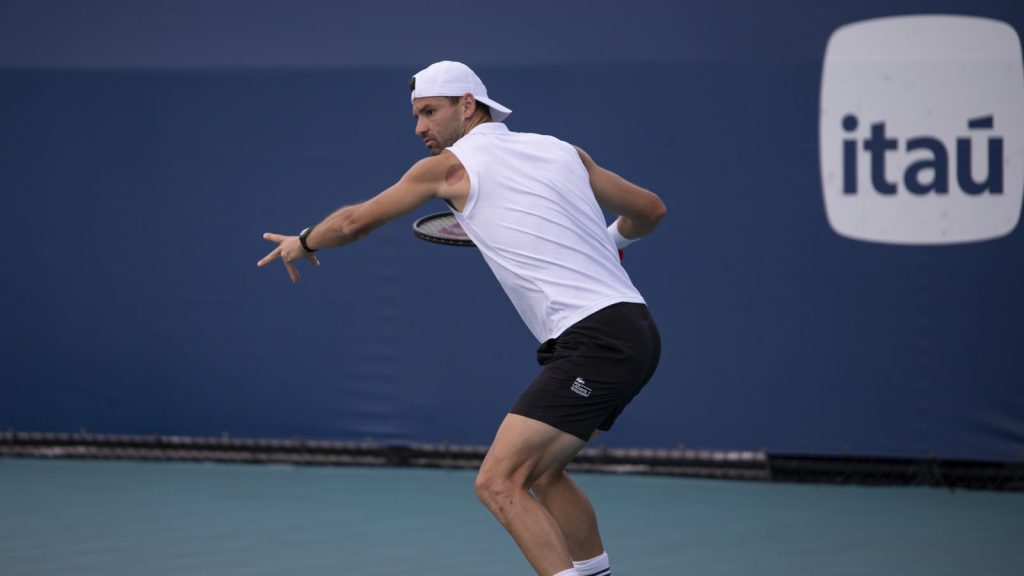 Grigor Dimitrov i forhåndens gennemsving med kasketten bagvendt på en blå hardcourt-bane ved Miami Open 2025