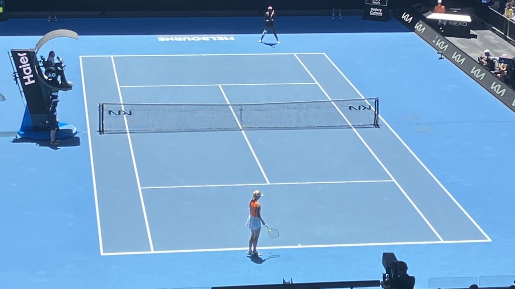 Blå hardcourt-bane i Melbourne Park set fra tribunen under Clara Tauson og Victoria Mbokos kamp ved Australian Open 2026